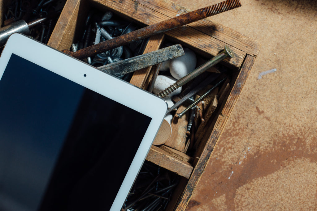 An iPad set on a wooden drawer containing rusty tools and implements as a metaphor for IEP non-compliance.