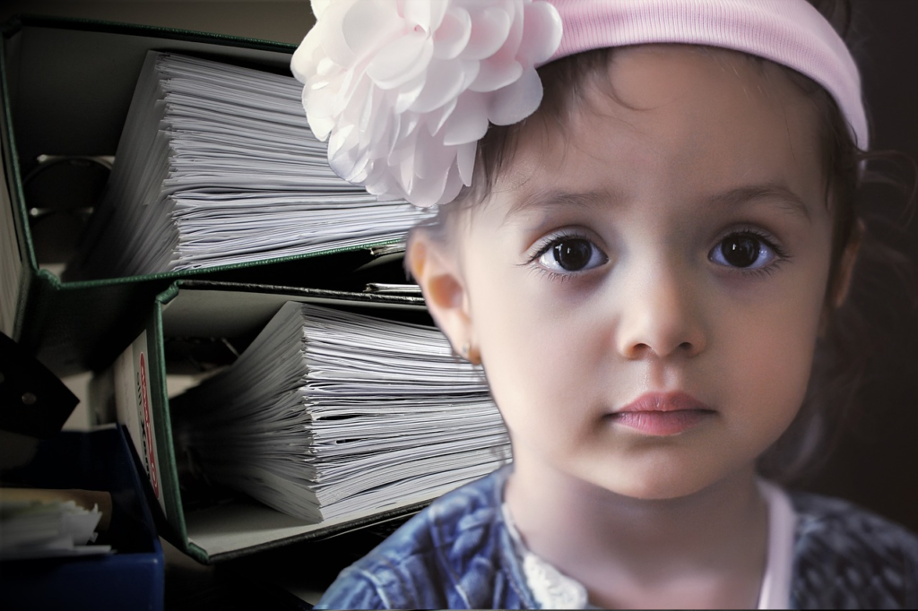 a girl sits in front of large binders containing private evaluations for an IEP